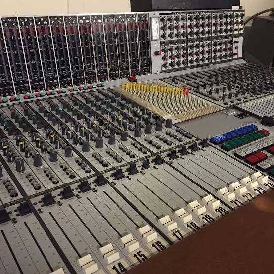 Console d'enregistrement de studio d'époque avec ses rangées de tranches, de boutons et de faders