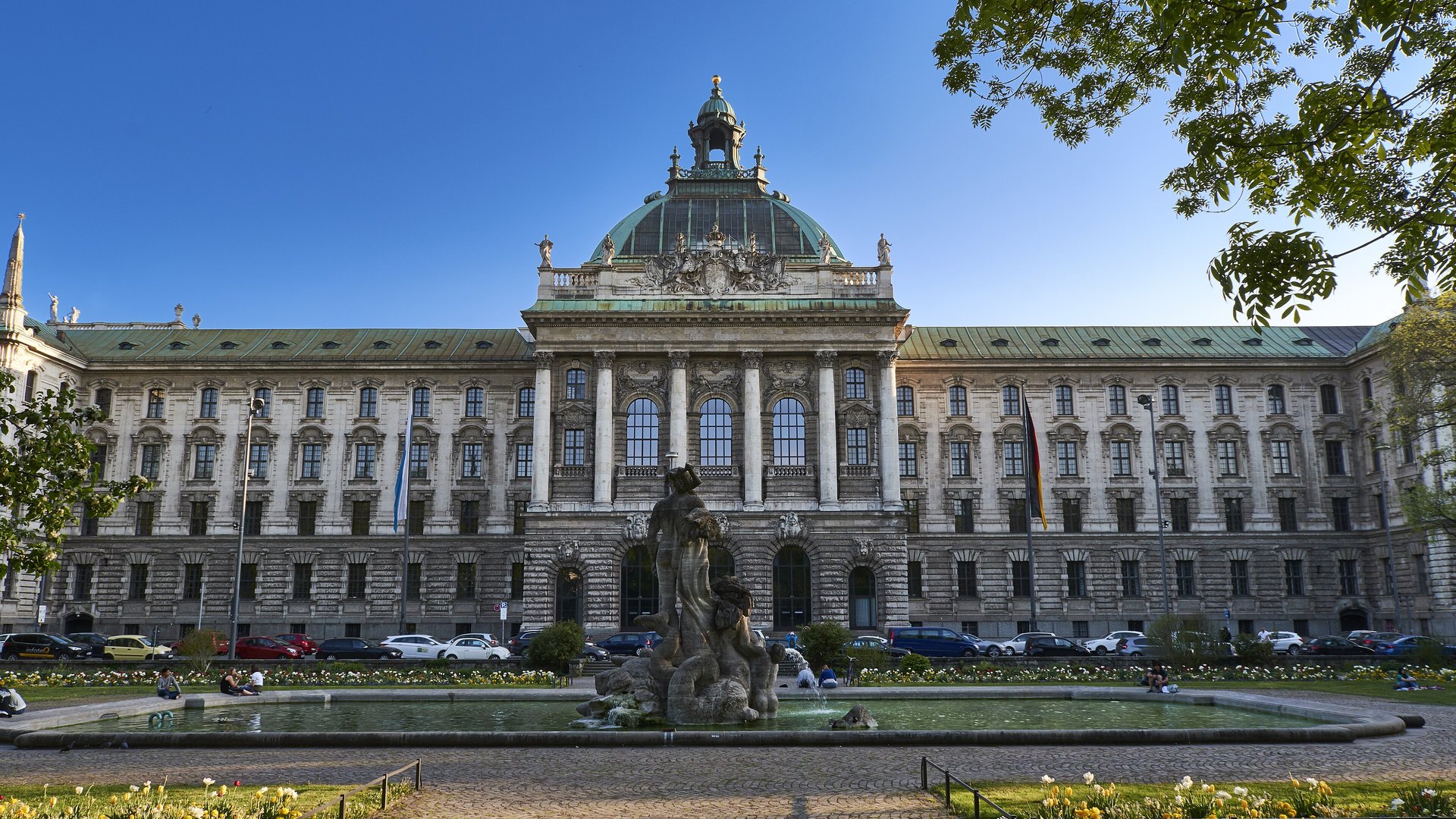 Le palais de justice de Munich, grand bâtiment à coupole verte, vu depuis la place et sa fontaine